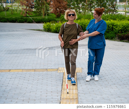 A nurse accompanies an elderly blind woman on a walk. A nurse accompanies an elderly blind woman on a walk. 115979861