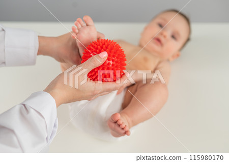 A doctor massages a baby's foot using a spiked ball. A doctor massages a baby's foot using a spiked ball. 115980170