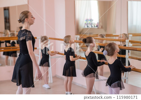 Caucasian woman teaches little girls ballet at the barre. 115980171