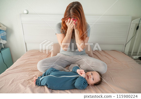 A woman sits on her child's bed and cries. Postpartum depression.  115980224
