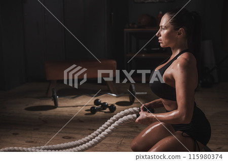 Caucasian woman posing with ropes in retro gym. Caucasian woman posing with ropes in retro gym. 115980374