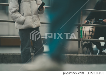 一名年輕人站在城市的街角操作智慧型手機 115980449