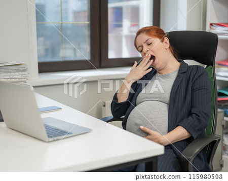 Pregnant woman sleeping at her desk in the office. Pregnant woman sleeping at her desk in the office. 115980598