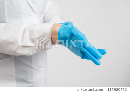 The doctor puts on latex gloves on a white background.  115980752
