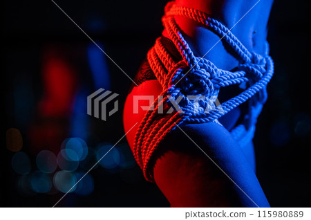 Close-up of a woman's belly in ropes tied using the Japanese shibari technique.  115980889