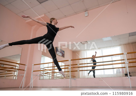 Caucasian blonde woman is practicing ballet in class. Ballerina rehearsing at the barre. Caucasian blonde woman is practicing ballet in class. Ballerina rehearsing at the barre. 115980916