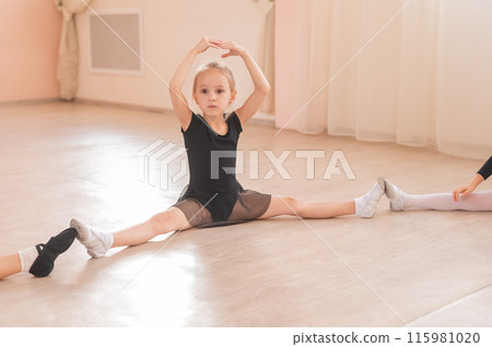 Little girls sit in a circle and do stretching at a ballet school. Little girls sit in a circle and do stretching at a ballet school. 115981020