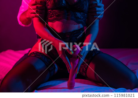 Man and woman in bedroom in red blue neon light using dildo. Man and woman in bedroom in red blue neon light using dildo. 115981021