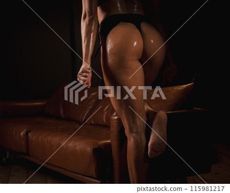 Close-up of a woman's tanned athletic buttocks oiled up. Close-up of a woman's tanned athletic buttocks oiled up. 115981217