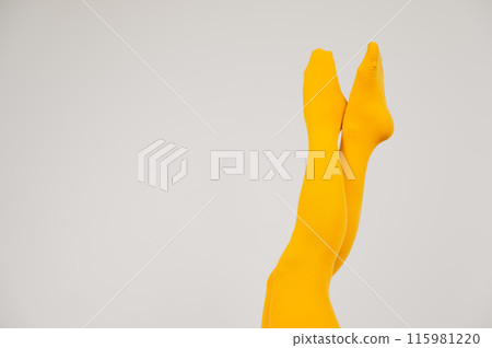 Female legs in ocher tights on a white background. Copy space.  115981220