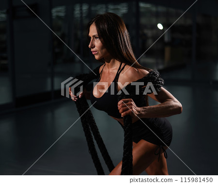 Caucasian woman posing with ropes in the gym. Caucasian woman posing with ropes in the gym. 115981450