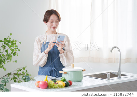 Woman checking cooking recipes on her smartphone (kitchen, housewife) Woman checking cooking recipes on her smartphone (kitchen, housewife) 115982744