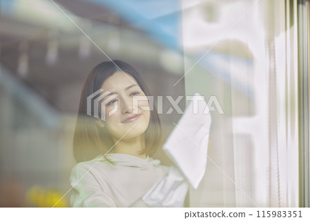 A middle-aged woman wiping windows in the living room A middle-aged woman wiping windows in the living room 115983351