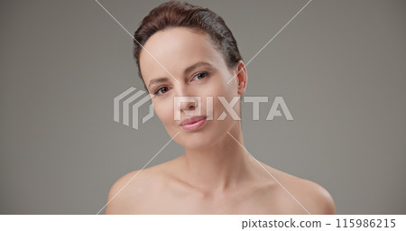 Beauty, health, cosmetics, anti-aging therapy and skin care concept - young beautiful brunette Caucasian woman touching face and looking at camera 115986215
