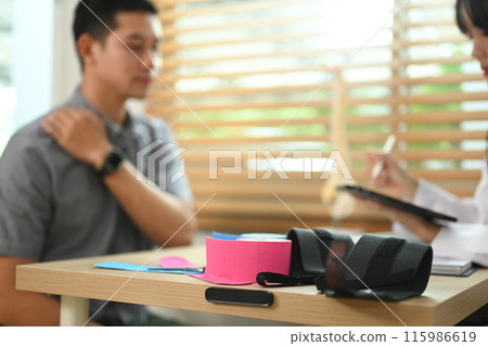 Kinesio tapes and scissors on table at physiotherapist office. Rehabilitation, treatment and healthcare concept Kinesio tapes and scissors on table at physiotherapist office. Rehabilitation, treatment and healthcare concept 115986619