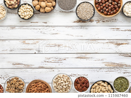 Mixed assorted nuts and seeds in various bowls on white wooden table and space for text Mixed assorted nuts and seeds in various bowls on white wooden table and space for text 115987460