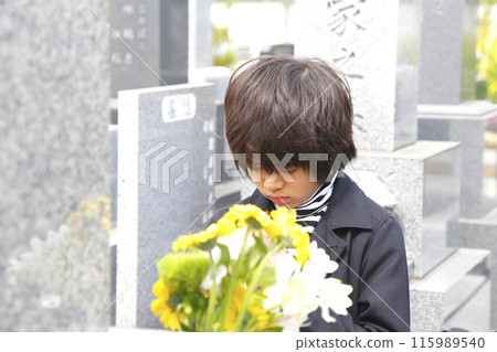 A boy praying in front of a grave A boy praying in front of a grave 115989540