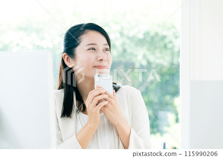 Young woman holding smartphone at work Young woman holding smartphone at work 115990206