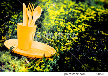 Camping.Yellow plastic dinnerware set.Cup,plate,fork,knife,spoon.Sunny meadow Camping.Yellow plastic dinnerware set.Cup,plate,fork,knife,spoon.Sunny meadow 115990503