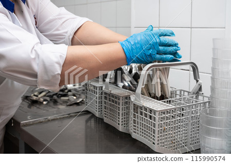 Unrecognizable woman, preparing dirty cutlery for washing at the dishwasher in commercial kitchen Unrecognizable woman, preparing dirty cutlery for washing at the dishwasher in commercial kitchen 115990574