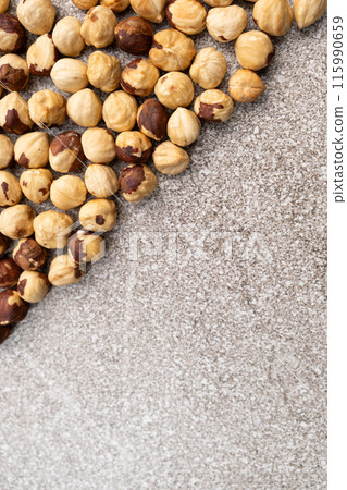 Roasted hazelnuts on a gray stone background top view, place for text Roasted hazelnuts on a gray stone background top view, place for text 115990659