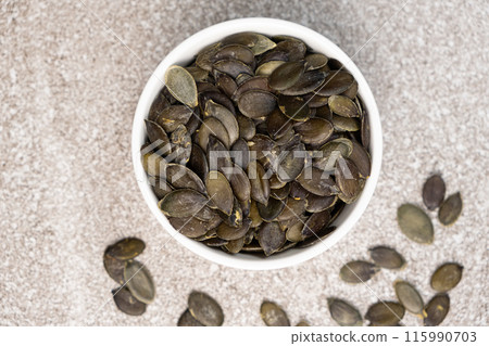 Peeled pumpkin seeds in plate on gray stone background, top view Peeled pumpkin seeds in plate on gray stone background, top view 115990703