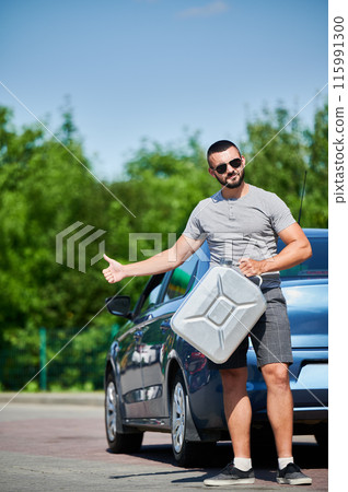 Man trying to catch passing car with gasoline canister in hand. Car runs out of fuel and stalled. Hoping someone drive him to gas station. 115991300