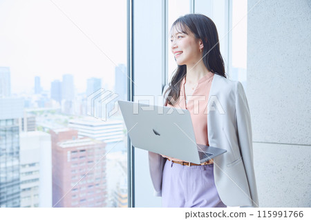 Woman looking at a computer by the window in an office 115991766