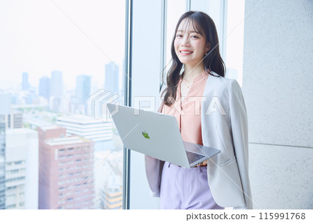 Woman looking at a computer by the window in an office 115991768
