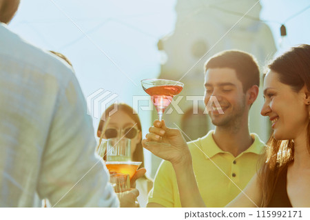 Friends gather for outdoor celebration, graduation party, their glasses raised high in toast to togetherness. Friends gather for outdoor celebration, graduation party, their glasses raised high in toast to togetherness. 115992171