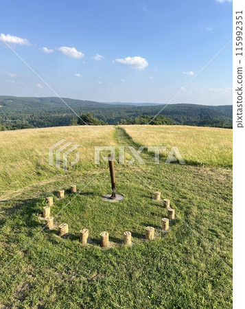A sundial made of wooden bars in a field among greenery with a beautiful view A sundial made of wooden bars in a field among greenery with a beautiful view 115992351