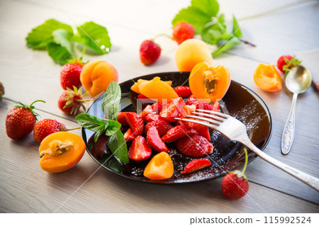 fresh fruit salad of ripe strawberries and apricots, on a light wooden table fresh fruit salad of ripe strawberries and apricots, on a light wooden table 115992524