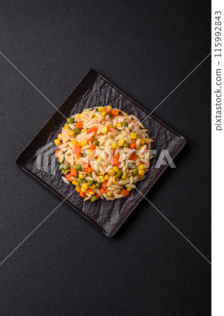 Delicious boiled rice with vegetables corn, carrots, peas with salt 115992843