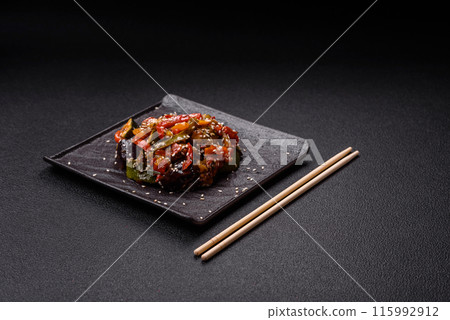 Spicy Asian dish with sliced meat fillet, hot pepper, carrots and sesame seeds 115992912