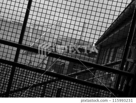 Satellite dish photographed trough a wire net. 115993231