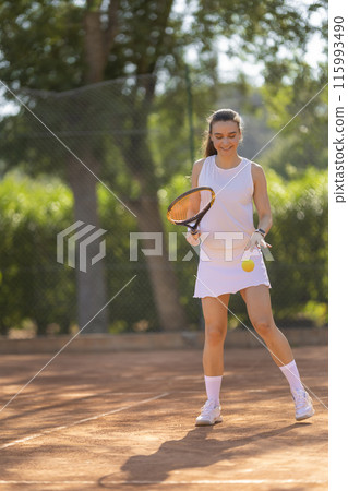 A woman is playing tennis on a court A woman is playing tennis on a court 115993490