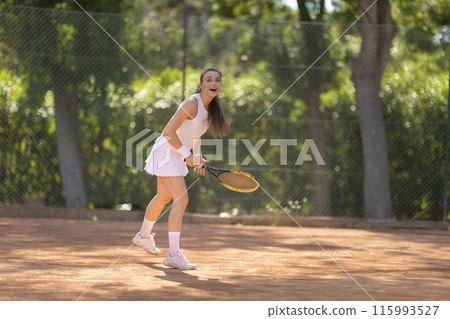 A woman is playing tennis on a clay court A woman is playing tennis on a clay court 115993527