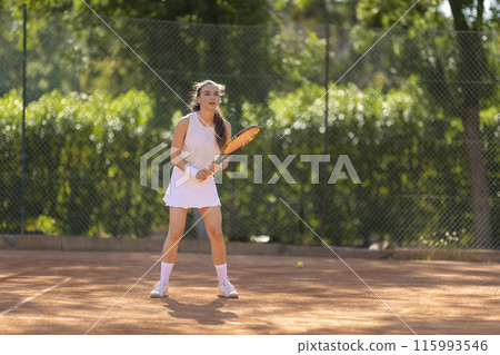 A woman is playing tennis on a court A woman is playing tennis on a court 115993546