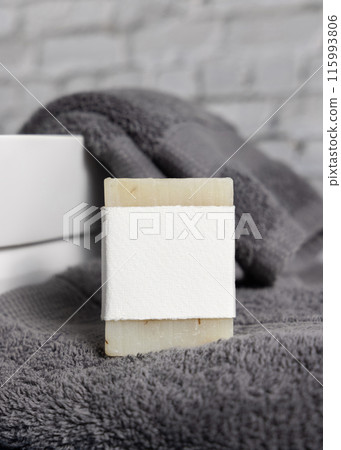 Soap bar with blank label on dark grey towels near vessel sink in bathroom closeup, mockup 115993806