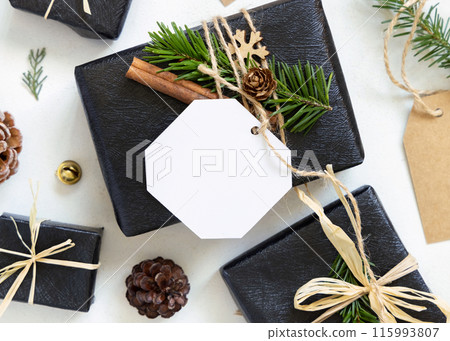 Black Christmas present with blank gift tag, decorated with fir branches, Mockup 115993807