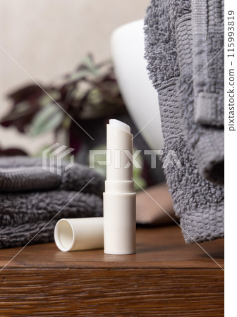 Opened lip balm stick on blue towels near cosmetics and basin in bathroom, mockup Opened lip balm stick on blue towels near cosmetics and basin in bathroom, mockup 115993819