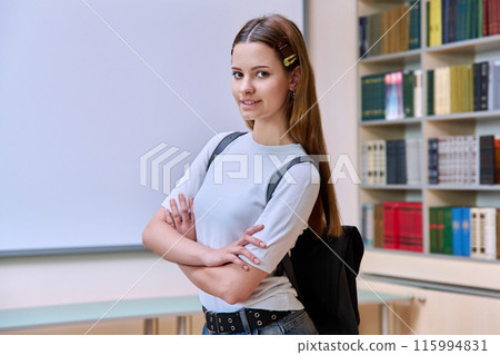 Portrait of teenage student girl with backpack in high school library classroom 115994831