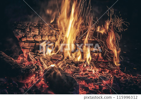 Campfire with sparks burning under night sky  Campfire with sparks burning under night sky  115996312