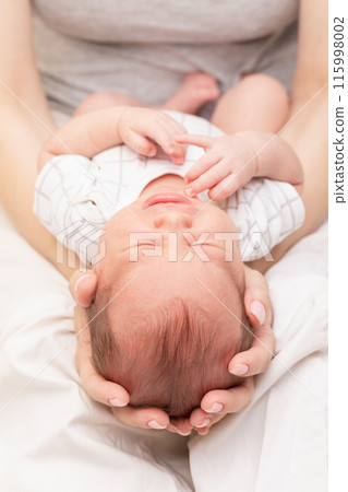 Mother Cradling Crying Newborn in Her Arms 115998002