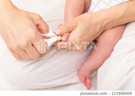 Mother cuts toenails of newborn 115998009