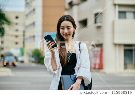 一個操作智能手機的年輕女子 一個操作智能手機的年輕女子 115998519