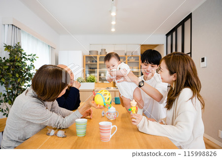 A smiling family of 5 people from 3 generations including senior grandparents and parents holding and soothing a baby. A smiling family of 5 people from 3 generations including senior grandparents and parents holding and soothing a baby. 115998826