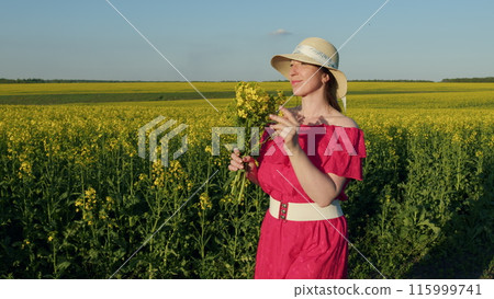 Beautiful Woman In Dress And Hat With Flower Bouquet, Enjoying Rapeseed Field. Portrait Of Young Brunette Female Wearing Hat With Rapeseed Bouquet. 115999741