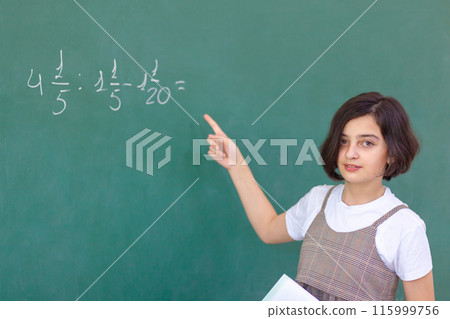 Beautiful girl at the blackboard solves a math problem 115999756