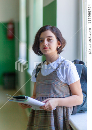 Beautiful girl in the school hallway reading a book 115999764
